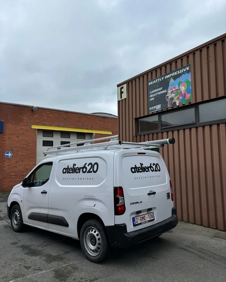 Witte bestelwagen met zwarte bedrijfsbelettering en een dakdrager