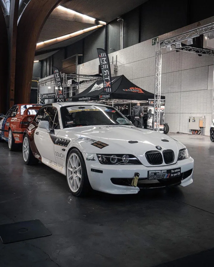 Witte racewagen met sponsorstickers in een werkplaats
